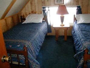 Una habitación con dos camas, una mesita y una ventana.