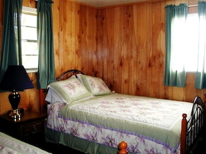 Una habitación con paneles de madera, una cama, una mesita de noche y una lámpara.