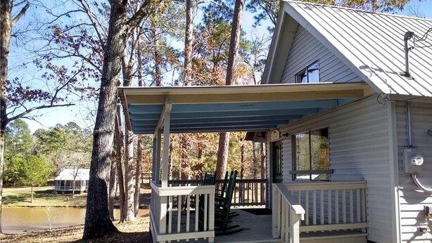 Een chalet met een overdekte veranda, een klein terras en uitzicht op een meer.
