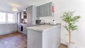 Eine moderne Küche mit grauen Schränken, einer Mikrowelle, einem Toaster und einem Blumentopf.
