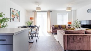 Ein modernes Wohnzimmer mit einer Couch, einem Esstisch, Stühlen und einem Fernseher.