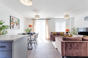 A modern living room with a sofa, dining table, chairs, and a TV. - The Fox Den - CM1, Chelmsford | 3-bed Stay - Pass the Keys (Chelmsford)