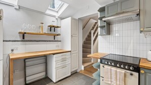 Una cucina con forno a incasso, un piano di lavoro in legno, un piccolo frigorifero e una scala che conduce a un altro livello.