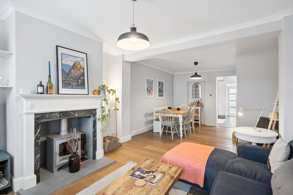 A living room with a fireplace, a dining area, and a kitchen in the background.