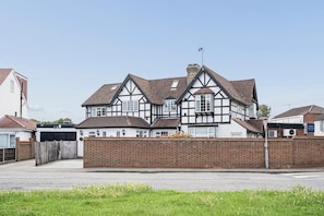 Ein Haus im Tudor-Stil mit einer Ziegelwand, einer Garage und einem klaren Himmel.
