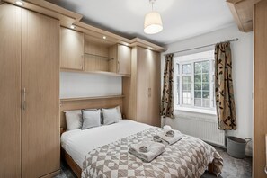 Ein Schlafzimmer mit einem Bett, einem Holzschrank und einem Fenster mit Vorhängen.