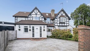 Una grande casa in stile Tudor con vialetto lastricato e muro in mattoni.