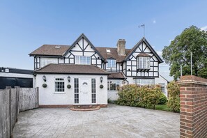 Ein großzügiges Haus im Tudor-Stil mit gepflasterter Auffahrt und einer Ziegelmauer.