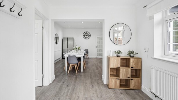 Un interno moderno con zona pranzo, un armadietto in legno con piante e un grande specchio.