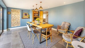 Un comedor con mesa de madera, sillas y lámparas colgantes.