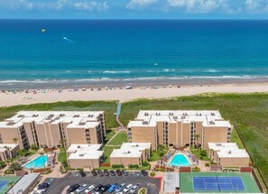 Ein Hotel mit mehreren Gebäuden, einem Schwimmbad und Blick auf den Strand.