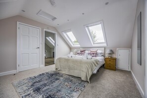 Une chambre avec un puits de lumière, un lit avec des oreillers, une table de chevet et une porte.