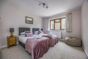 Ein Schlafzimmer mit zwei Betten, einem Nachttisch, einem Spiegel, einem Fenster mit Vorhängen und einer Deckenleuchte.