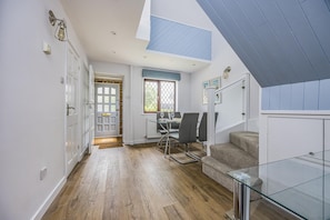 Un interior moderno con zona de comedor, escalera y vistas al exterior.