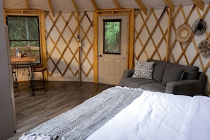 Una habitación acogedora con cama, sofá, mesa y taburetes, además de una puerta con ventana.
