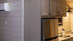 A circular skylight in a wooden ceiling, a stainless steel refrigerator, and a kitchen with white cabinets. - Fully-Equipped Yurt Rental for Memorable Family Vacations in Livingston, Texas (Livingston)