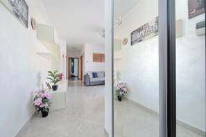 A hallway with a sofa, a coffee table, and a potted plant.