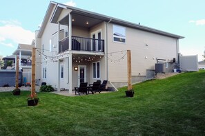 Ein zweistöckiges Haus mit Balkon, Sitzgelegenheit im Freien und Lichterketten.