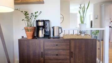 A wooden cabinet with a coffee maker, two potted plants, and a wicker basket.