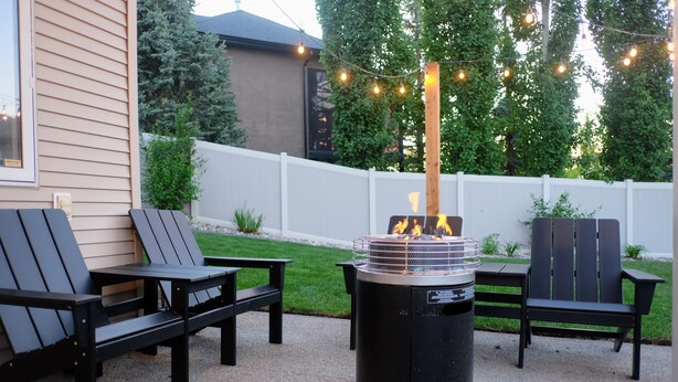 Un patio exterior con un brasero, dos sillas Adirondack y una mesa.
