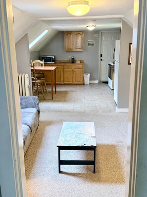 A narrow hallway with a dining area, kitchen, and a small table with a map.