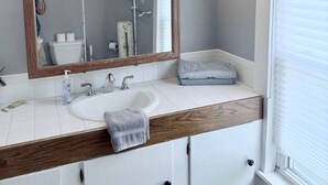 A bathroom with a wooden vanity, a large mirror, a sink, and a towel rack.
