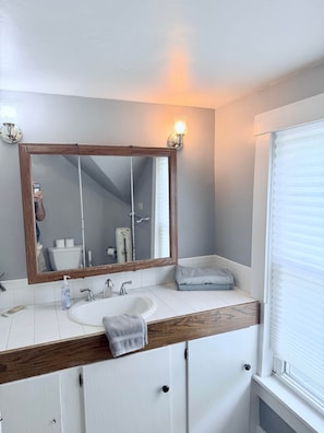 A bathroom with a wooden vanity, a large mirror, a sink, and a towel rack.