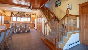 Eine geräumige Küche mit Holzausbau, ein Essbereich mit Stühlen und eine Treppe mit Holzgeländern.