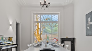 A dining room with a piano, a stained glass window, and a fireplace. - Grand Ostend townhouse with sauna near the sea (Oostende)