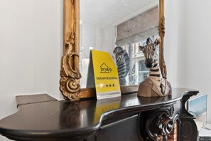 A black table with a yellow sign, a zebra statue, and a mirror reflecting a window.