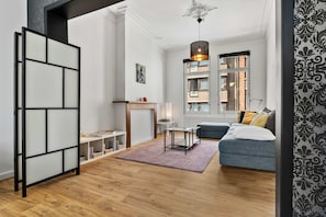 A modern living room with a sofa, a table, a bookshelf, and a decorative hanging light fixture.