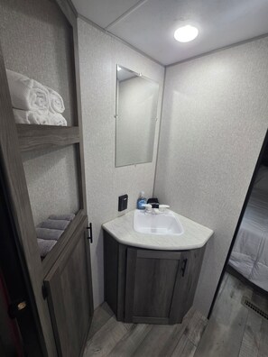 A bathroom with a built-in sink, a mirror, and a towel rack with towels.