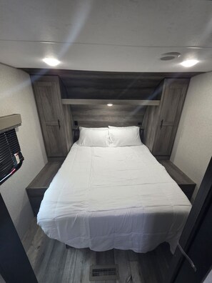 A bedroom with a bed, wooden headboard, and built-in storage cabinets.
