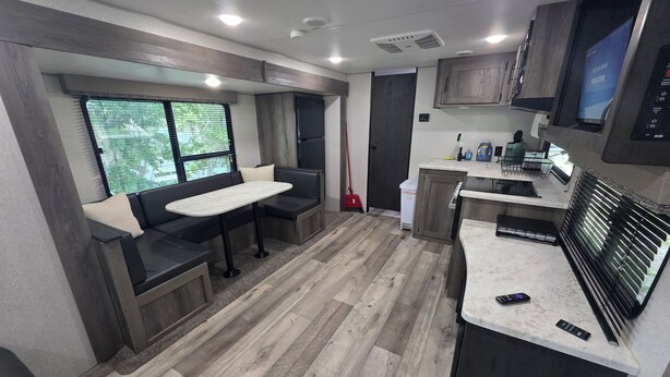 Et moderne camper-køkken med spiseplads, trægulv og indbyggede apparater.