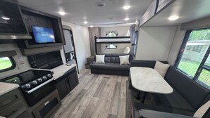 En kompakt indretning i en autocamper med et tekøkken, siddepladser og et fjernsyn.