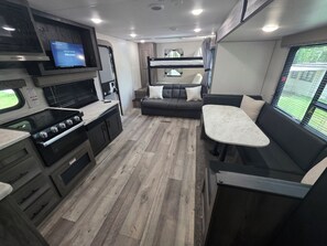 Un intérieur de camping-car compact comprenant un coin cuisine, un espace salon et un téléviseur.