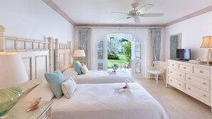 Habitación de hotel con dos camas, televisión, escritorio con lámpara y vistas al exterior.