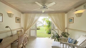 Una habitación con escritorio, silla y vistas a un jardín.