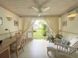 Ein Zimmer mit Schreibtisch, Stuhl und Blick auf einen Garten.