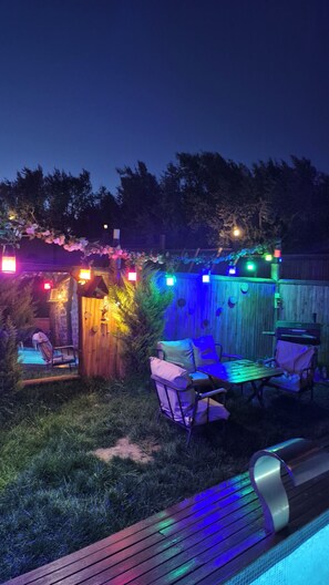 A backyard with a wooden deck, a seating area with chairs and a table, and a wooden fence. - İznik Kuzeymen Bungalov & Lüx taş ev (İznik)