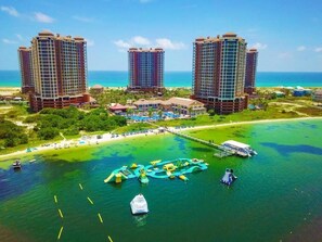 A resort with high-rise buildings, a pool area, and a pier extending into the water. - 2 Bedroom Portofino Resort Condo in Beautiful Pensacola Beach- Gym, Spa, Pool (Pensacola Beach)