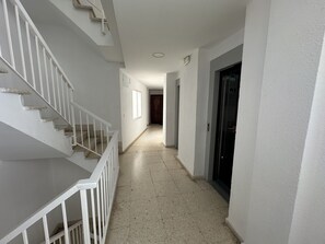 Ein Flur mit Treppe, einer Tür und einer Lampe.