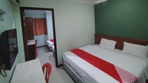 Ein Hotelzimmer mit Bett, Schreibtisch, Stuhl und Fernseher.