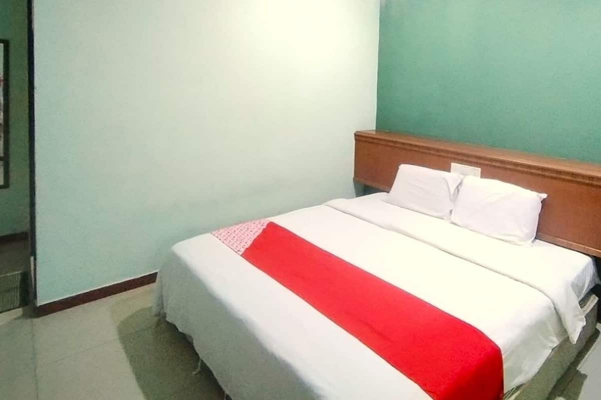 Een hotelkamer met een bed, een houten hoofdeinde en een groene wand.