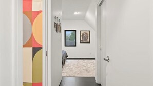A hallway leading to a bedroom with a bed, a window, and a door. - Upscale Parkside Living: Modern 1 bed & bath with All Utilities included (Columbus)