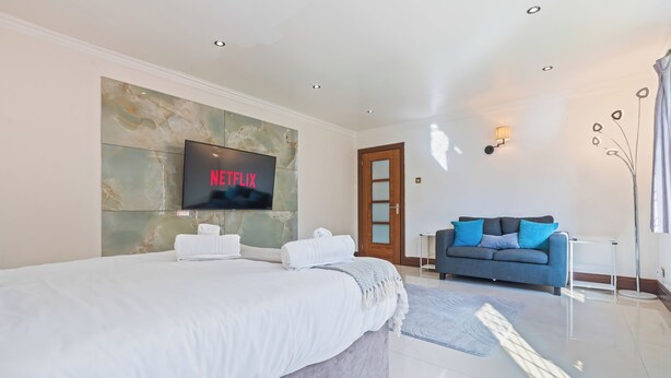 Ein modernes Hotelzimmer mit einem großen Bett, einem Flachbildfernseher, einer Couch und einem Wandbild.