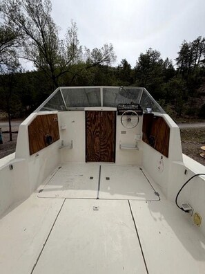Interior de un barco, con timón, panel de control y paneles de madera.