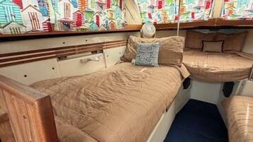 A narrow, enclosed cabin with a bunk bed, a small table, and a patterned wall.