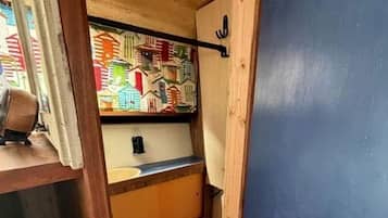 Un couloir étroit avec une porte en bois, un petit lavabo et une fenêtre aux couleurs vives.