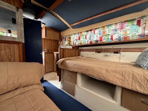 A compact interior with two beds, a small kitchenette, and a colorful wall mural. - Rustic Boat Glamping Retreat with Mountain Views near Rio Peñasco in Mayhill, New Mexico (Mayhill)